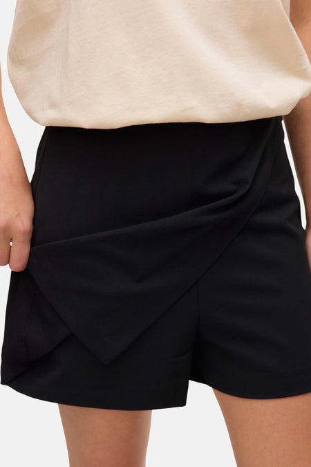 Zwarte skort van VERO MODA, met een overslagdetail aan de voorkant, gecombineerd met een beige top.
