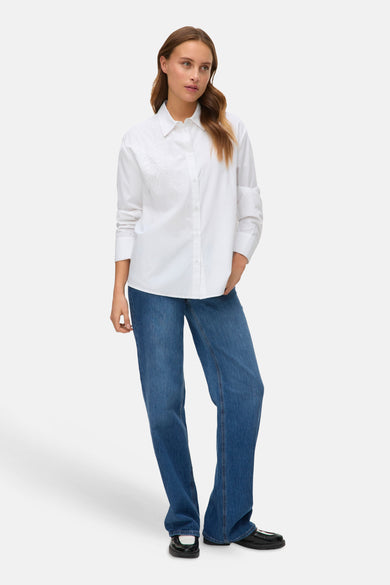 Wit, lang mouwen hemd van VERO MODA, met een subtiel bladmotief, gecombineerd met blauwe jeans en zwarte schoenen.
