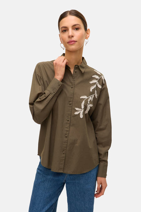 Chemise kaki à longues manches de VERO MODA, avec motif de feuille sur l'avant et jeans bleus.