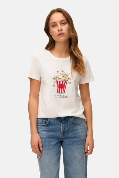 T-shirt blanc à manches courtes de VERO MODA® avec un imprimé d'un verre de popcorn et le texte "Le Cinéma", porté avec un jean.
