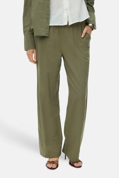 Pantalon vert de VERO MODA, à jambes larges et porté avec une blouse blanche et des talons.