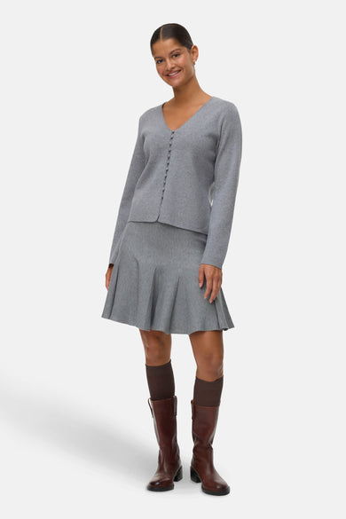 Korte grijze rok van VERO MODA®, gecombineerd met bruine laarzen en donkere sokken.
