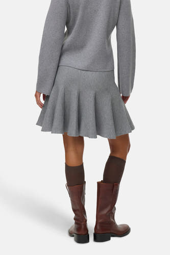 Grijze korte rok van Vero Moda, met een uitlopend model en gecombineerd met bruine laarzen en sokken.

