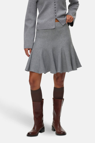 Korte grijze rok van VERO MODA, met plooien en gecombineerd met bruine laarzen en sokken.