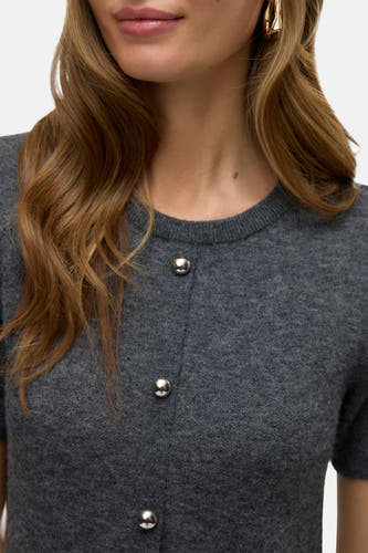 Grijs jurkje met korte mouwen van VERO MODA®, met zilveren knopen en golvend blond haar.
