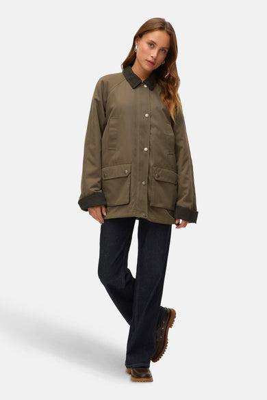 Veste courte verte de VERO MODA, avec des manches longues et un pantalon denim foncé et des chaussures en cuir marron.