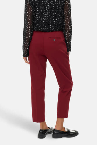 Rode broek van VERO MODA met een knoopzakje, gecombineerd met een zwart-wit gestreepte blouse en zwarte loafers.
