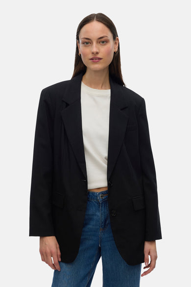 Zwarte blazer van VERO MODA, met reverskraag en zakken, gedragen over een wit shirt en jeans.