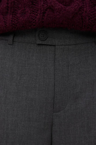 Pantalon gris de VERO MODA, avec un détail de nœud et une pièce de tissu brodée rouge foncé au-dessus.