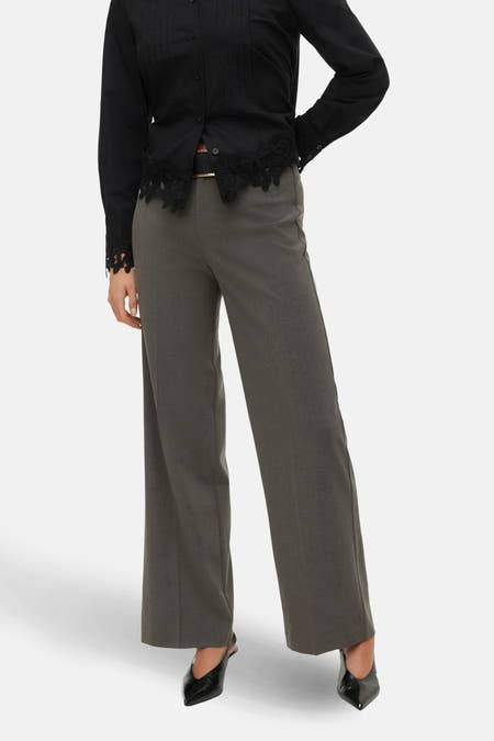 Grijze broek van VERO MODA, met wijde pijpen en gedragen met een zwarte blouse.

