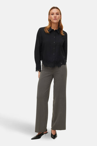 Grijze broek van VERO MODA, met wijde pijpen en gecombineerd met een zwarte blouse en zwarte schoenen.
