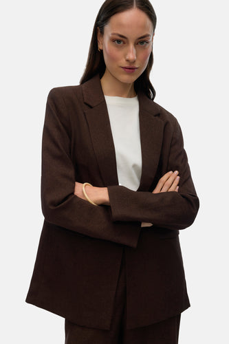 Vrouw in bruin pak met gekruiste armen.