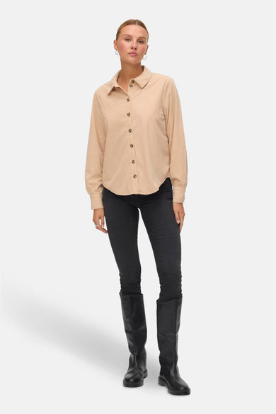 Chemise beige de VERO MODA, portée avec des jeans noirs et des bottes noires.