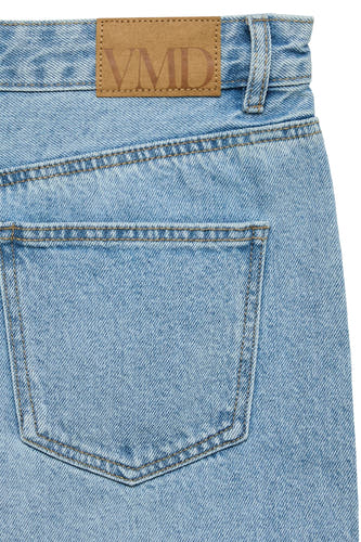 Short en jean bleu clair de VERO MODA avec coutures apparentes et un logo marron 'VMD' sur la ceinture.