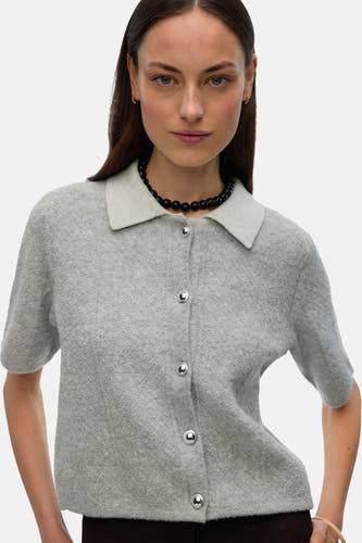 Grijs gilet van VERO MODA, met korte mouwen, kraag en knoopsluiting, gecombineerd met een zwarte ketting.
