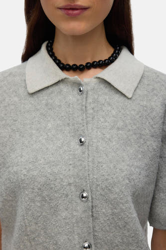 Grijze gilet van VERO MODA met zilverkleurige knopen en een kraag, gedragen met een zwarte kralenketting.