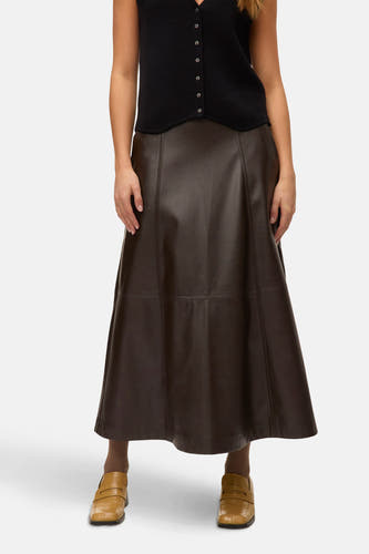 Lange bruine rok van VERO MODA, met decoratieve stiksels, gecombineerd met een zwarte top en bruine loafers.

