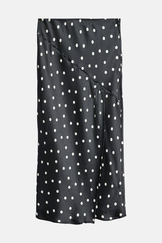Lange zwarte rok van VERO MODA® met witte stippen en een split aan de voorkant.
