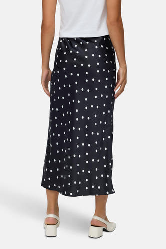 Lange zwarte rok van VERO MODA® met witte stippen, gecombineerd met wit shirt en ecrukleurige schoenen.

