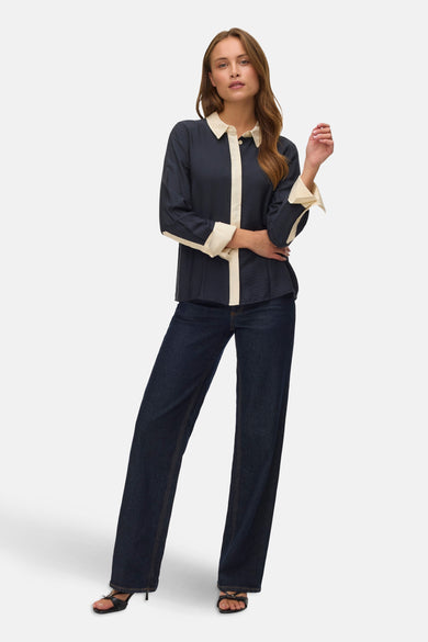 Chemise noire à manches longues de VERO MODA®, avec des accents crème et portée avec un jeans foncé.