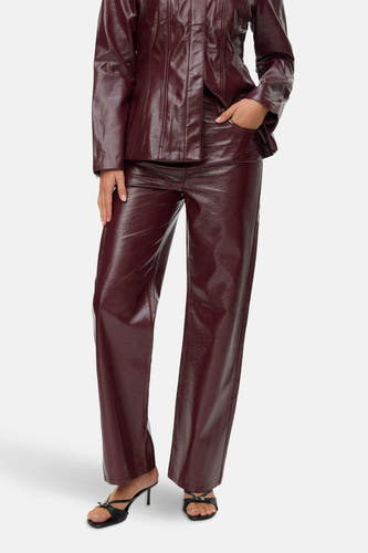 Bordeaux broek van VERO MODA®, met een glanzende textuur en gecombineerd met zwarte muiltjes met hak.

