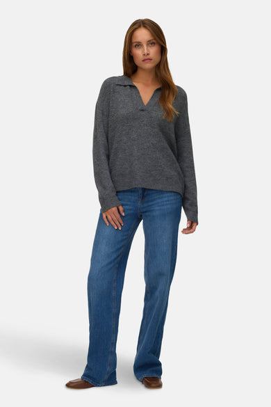 Pull à col V gris de VERO MODA®, porté avec des jeans bleus et des chaussures marrons.