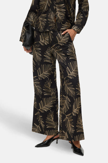 Zwarte broek van VERO MODA, met gouden bladmotief en wijde pijpen.