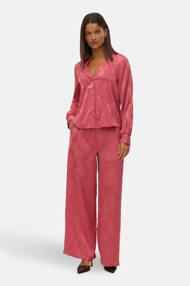 Roze broek van Vero Moda, met bloemdessin, gecombineerd met een roze blouse en bruine schoenen.