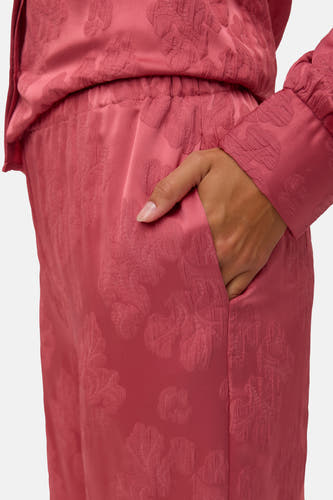 Pantalon rose de VERO MODA, avec un motif floral subtil et une main dans la poche.