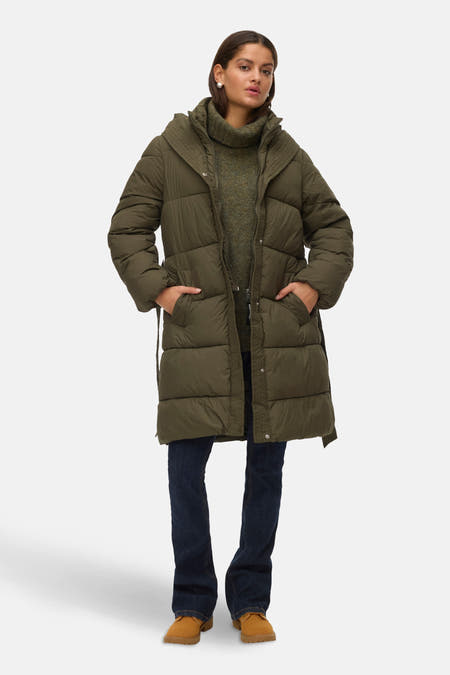 Manteau long vert de VERO MODA, avec un capuchon et une ceinture, porté avec des jeans foncés et des chaussures marrons.