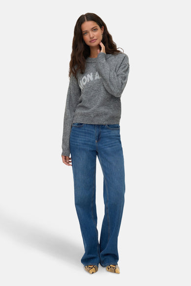Sweat-shirt gris à col rond de VERO MODA, avec impression sur le devant, associé à des jeans bleus et des chaussures à imprimé serpent.