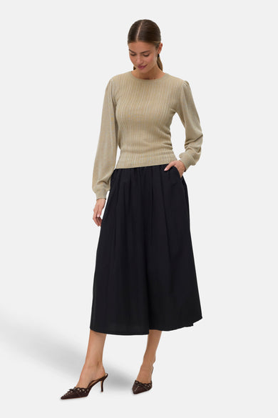 Groene trui met ronde hals van VERO MODA®, gedragen met een zwarte midi-rok en bruine hakken.