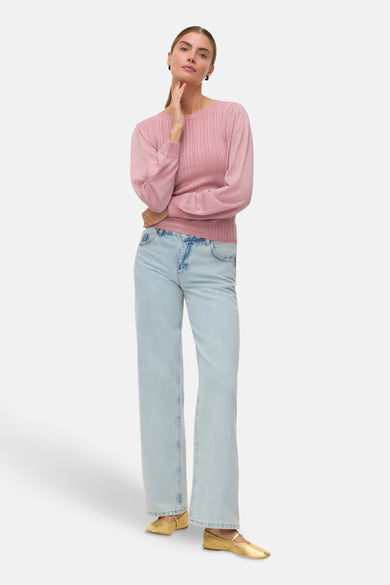 T-shirt rose avec col rond de VERO MODA, texture rayée, associé à des jeans bleu clair et des ballerines dorées.