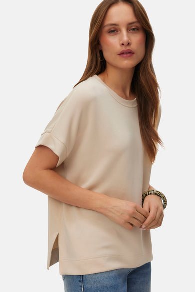 T-shirt écru à manches courtes de VERO MODA, porté avec des jeans larges et des chaussures noires.