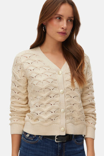 Veste écru de VERO MODA, avec fermeture à boutons et un motif tricoté ajouré, associée à des jeans foncés et des chaussures noires.