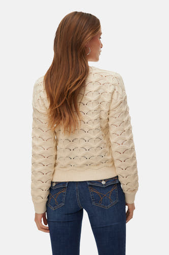 Gilet écru de VERO MODA® avec un motif tricoté ouvert et des manches longues, associé à un pantalon de travail foncé.