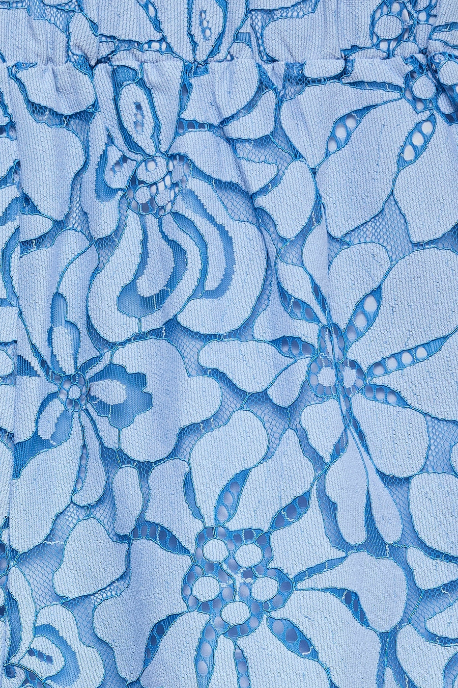 Detail van een lichtblauwe short van VERO MODA met een kanten bloemenpatroon.