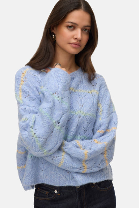 Blauwe trui met ronde hals van VERO MODA, met geel en groen ruitpatroon, gedragen met donkere jeans.
