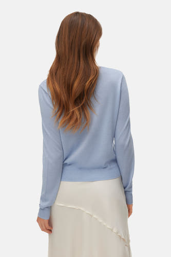 Blauwe cardigan van VERO MODA®, gezien van achteren, gedragen met een crèmekleurige rok.