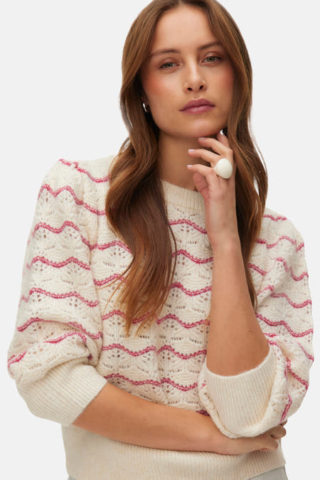 Rode trui met ronde hals van VERO MODA®, gebreid in een golvend patroon, gecombineerd met een witte ring.