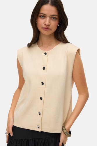 Veste écru de VERO MODA®, avec des boutons noirs, associée à une jupe maxi noire et des chaussures noires.