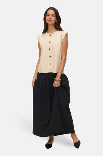 Ecru vest van VERO MODA®, met zwarte knopen, gecombineerd met een zwarte maxi-rok en zwarte schoenen.