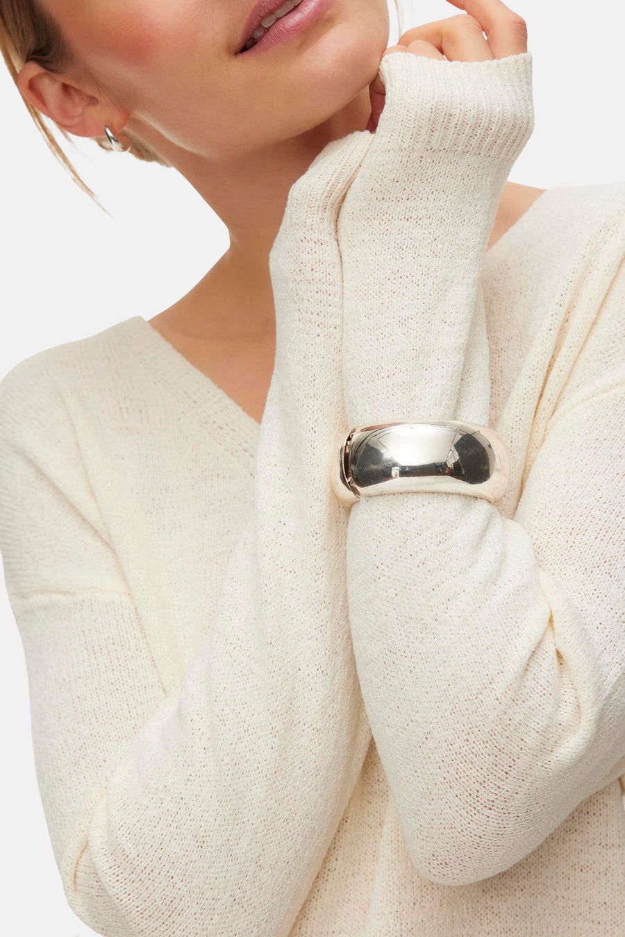 Pull col en V écru de VERO MODA®, porté avec un bracelet argenté, en vue recadrée.