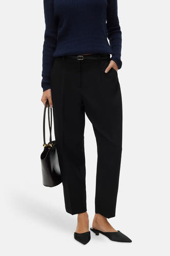 Pantalon noir de VERO MODA, avec une ceinture fine et un sac à main.