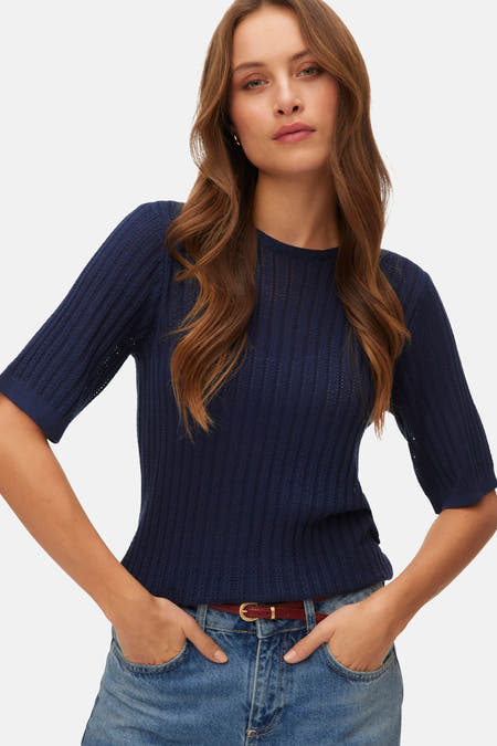 Blauwe trui met ronde hals van VERO MODA, met korte mouwen en een fijn gebreid patroon, gecombineerd met jeans en een riem.