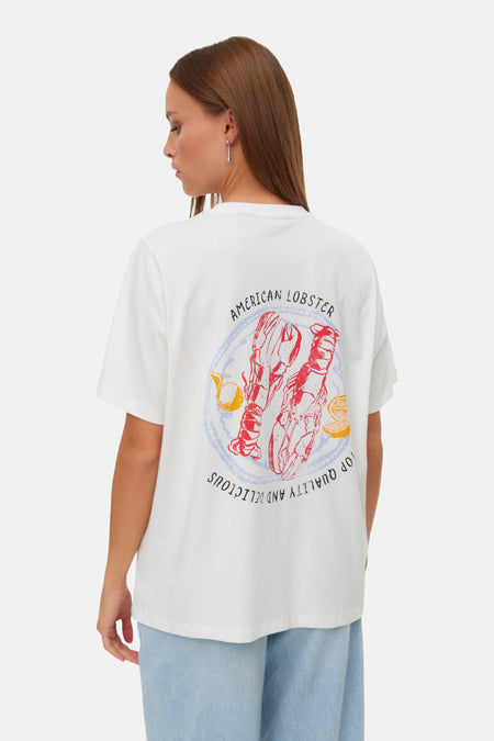 Wit T-shirt van VERO MODA® met rugprint van rode kreeften, citroenen en tekst, gedragen met lichte jeans.