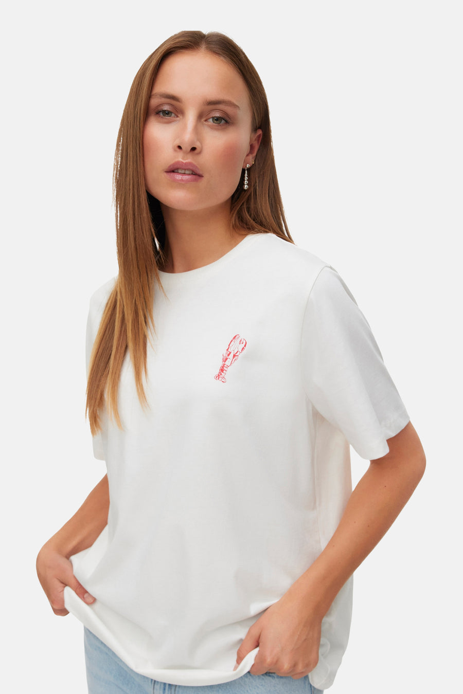 Wit T-shirt van VERO MODA met rode kreeftenprint, gedragen door model met spijkerbroek en oorbellen.