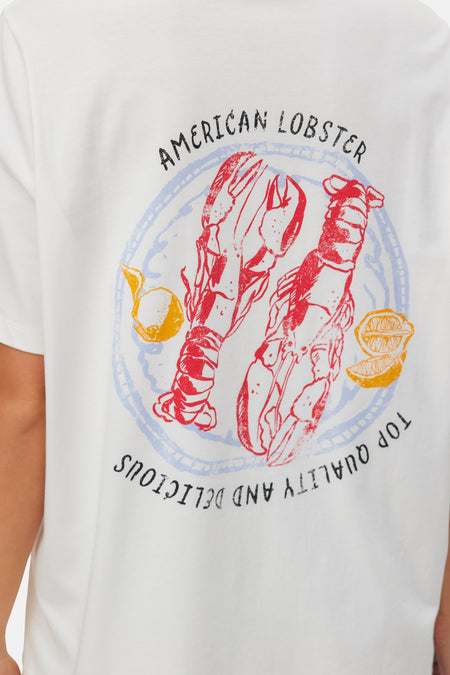 T-shirt blanc à manches courtes de VERO MODA® avec imprimé graphique de homards rouges, citrons jaunes, textes noirs et bordure bleue.