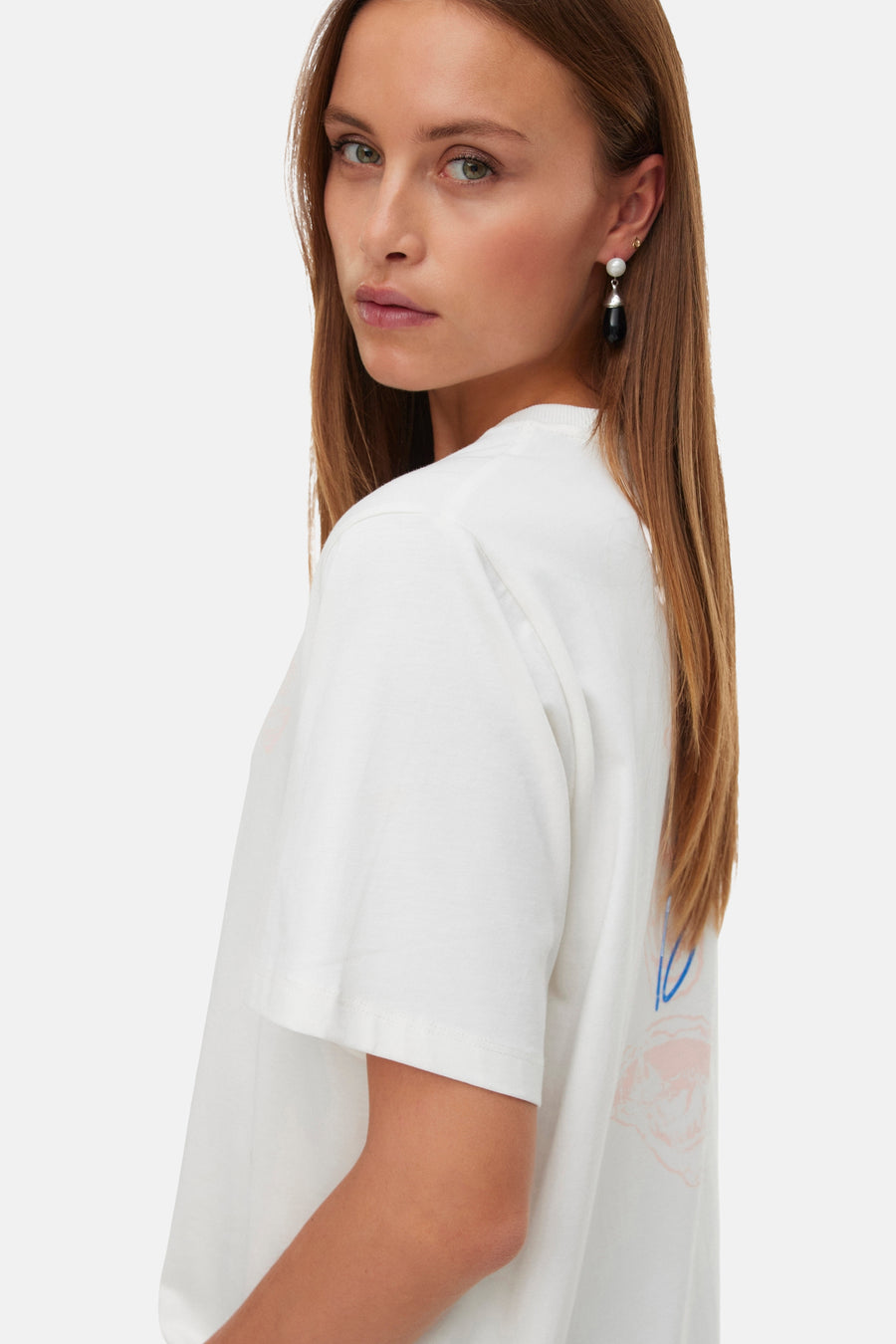 Wit T-shirt met korte mouwen van VERO MODA met abstracte roze en blauwe print op de rug, gedragen door een model in zijprofiel.