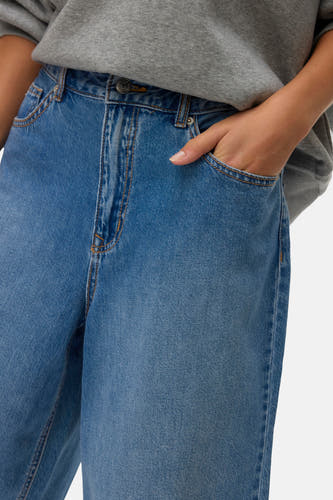 Blauwe denim short van VERO MODA, met steekzak, gedragen met een grijze trui.
